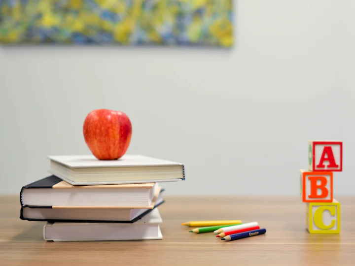 Stack of books with an apple, alphabet blocks and crayons