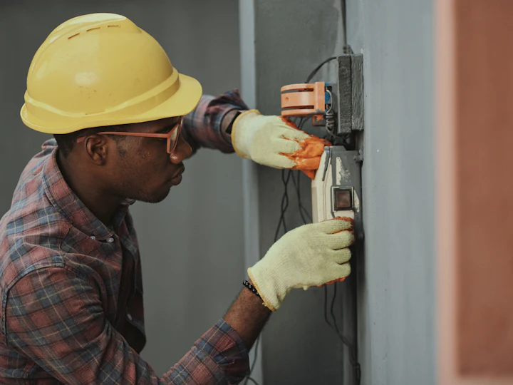 Electrician in a hard hat working on a fuse box
