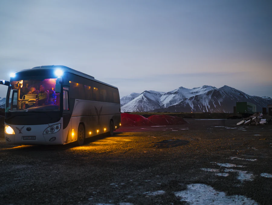 Coach bus parked at dusk with mountains behind